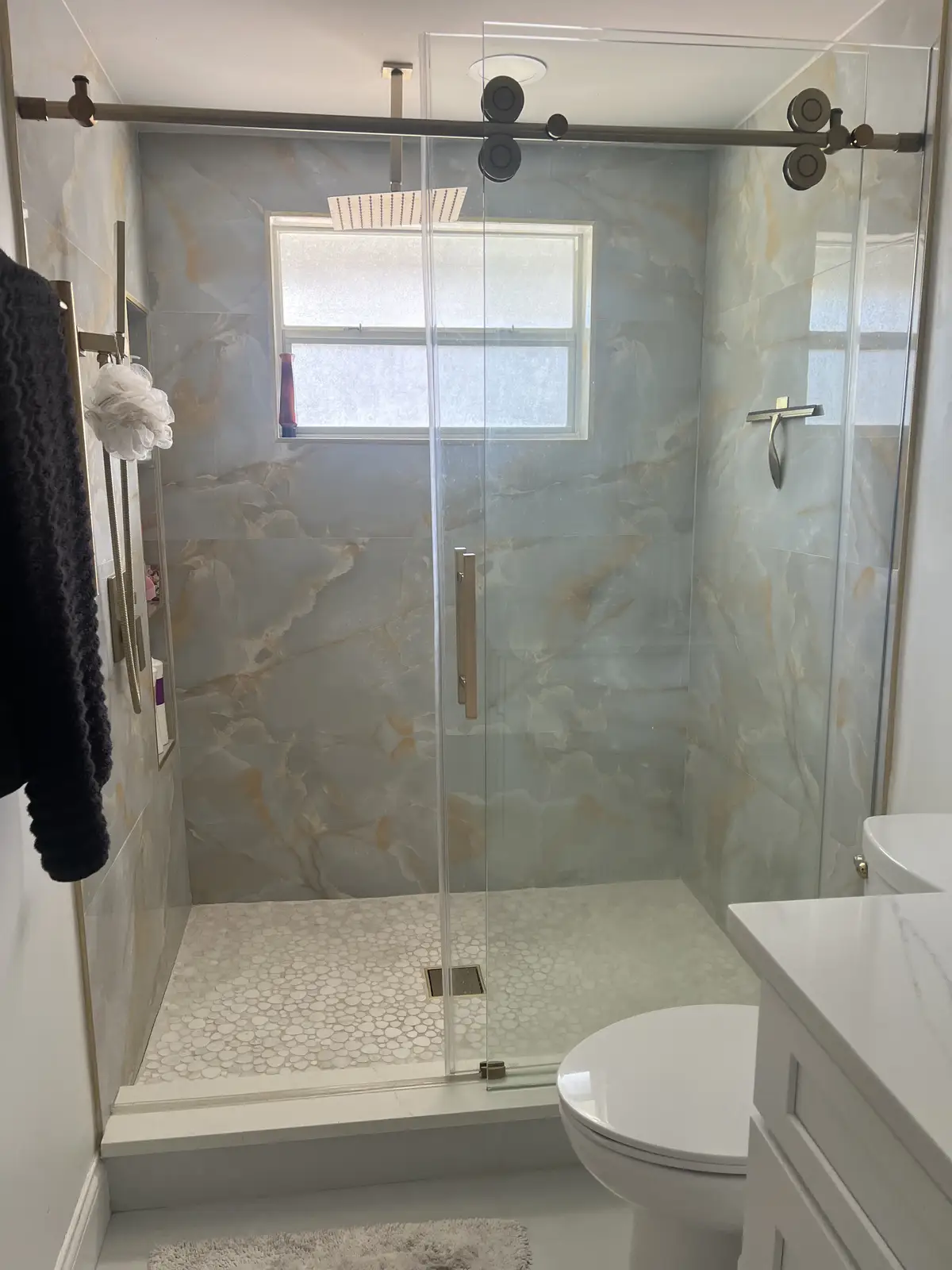 Frameless glass shower with stone walls and quartz curb by Venet LLC in Tampa Bay, Florida