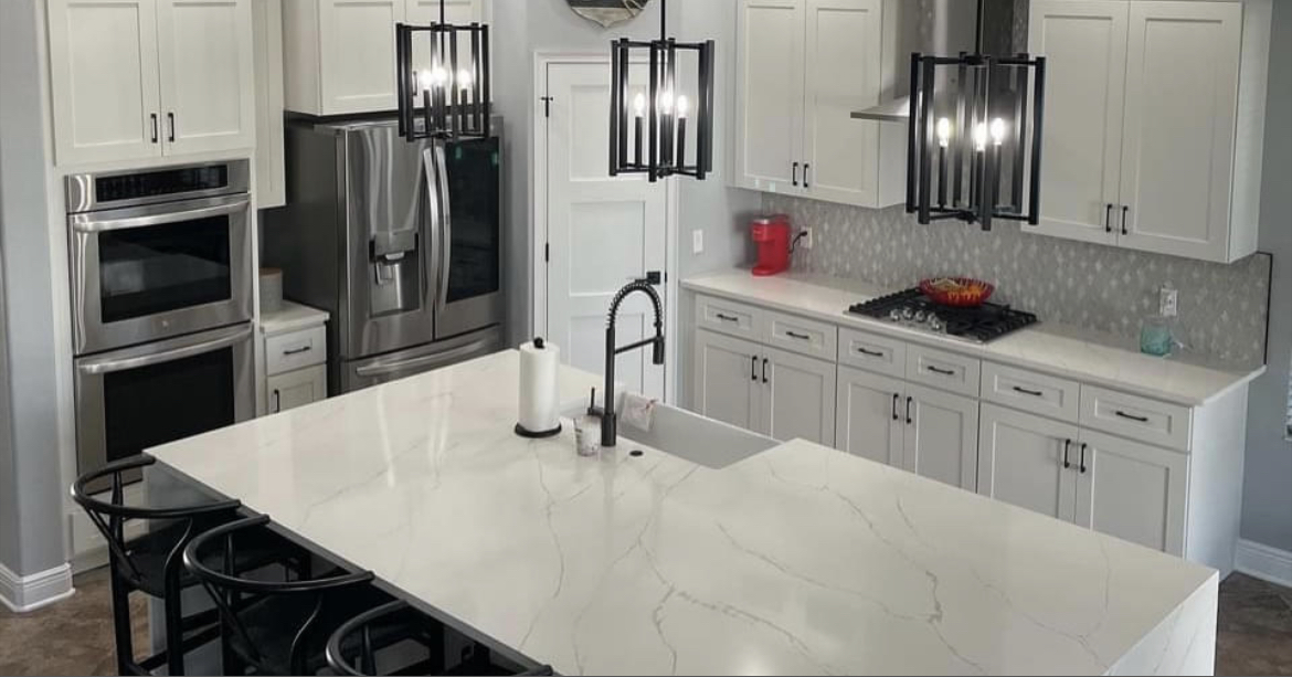 Bright modern Tampa Bay kitchen with white marble-look quartz waterfall island, custom cabinetry, and black fixtures by Venet Stones