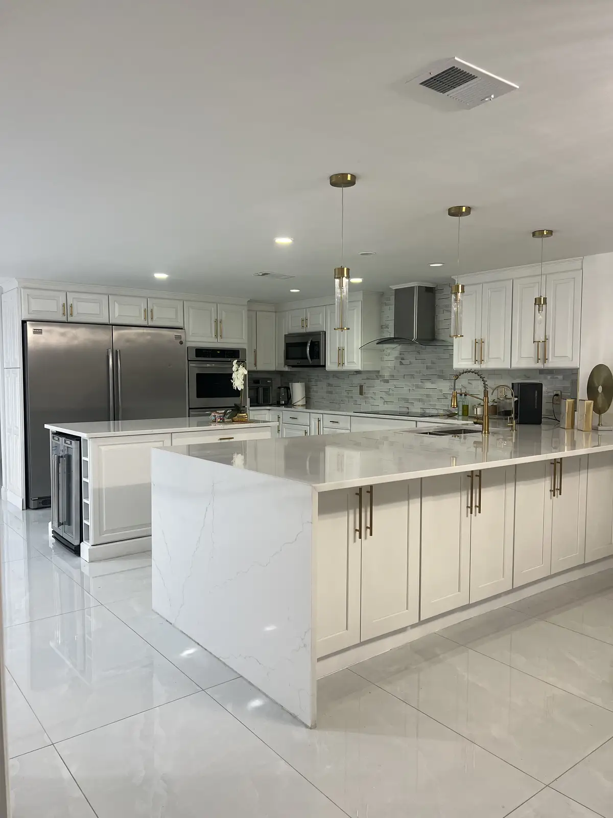White quartz waterfall island in a modern white kitchen by Venet LLC in Tampa Bay, Florida
