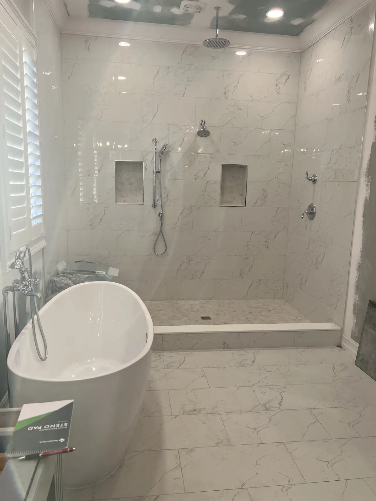 Marble tile walk-in shower with freestanding tub in a master bathroom by Venet LLC in Tampa Bay, Florida