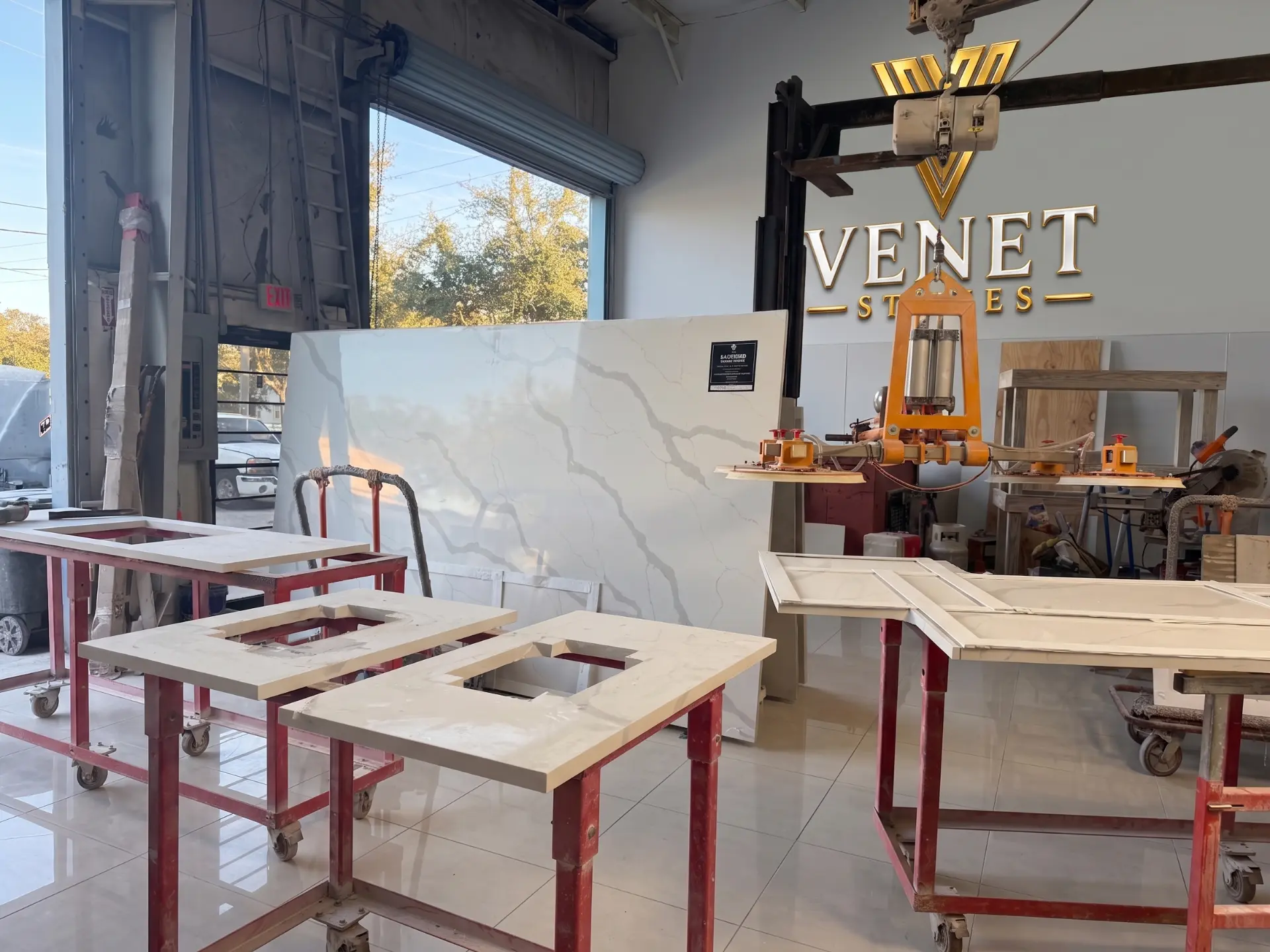 Venet Stones workshop with custom stone countertops on fabrication carts beneath the company logo in Tampa Bay