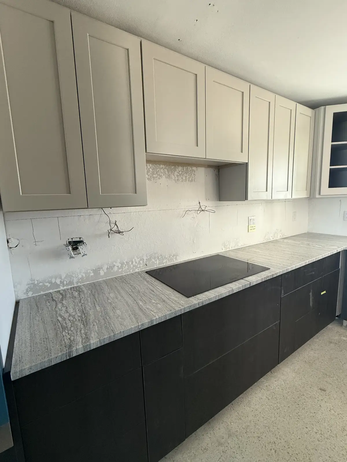 Modern kitchen with black cabinets and veined stone countertops by Venet LLC in Tampa Bay, Florida