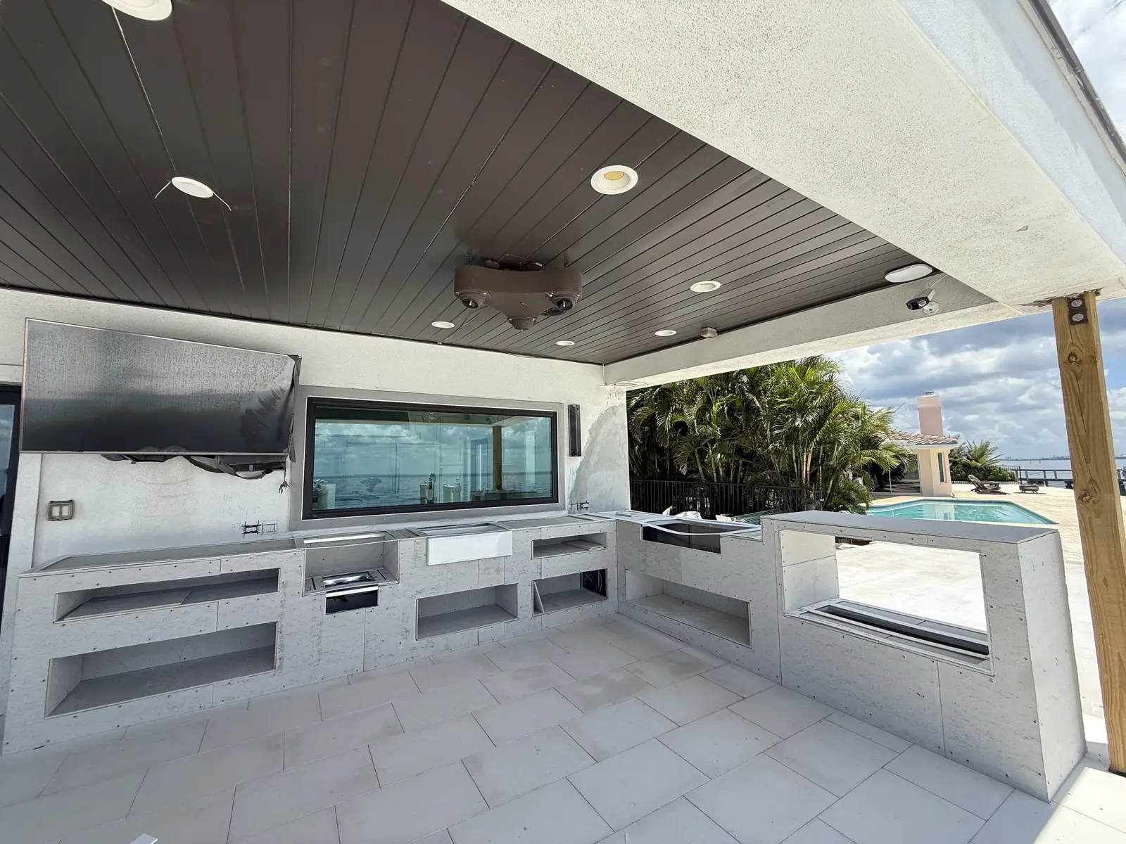 Poolside outdoor kitchen with quartz countertops and built-in grill by Venet LLC in Tampa Bay, Florida