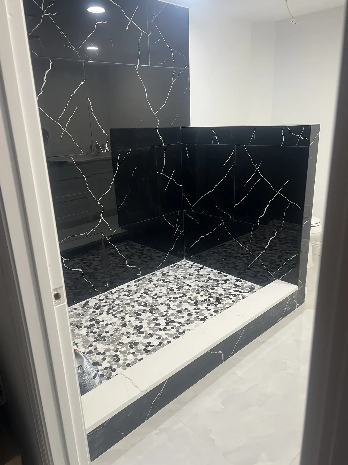 Black marble fireplace surround with glass rock bed by Venet LLC in Tampa Bay, Florida