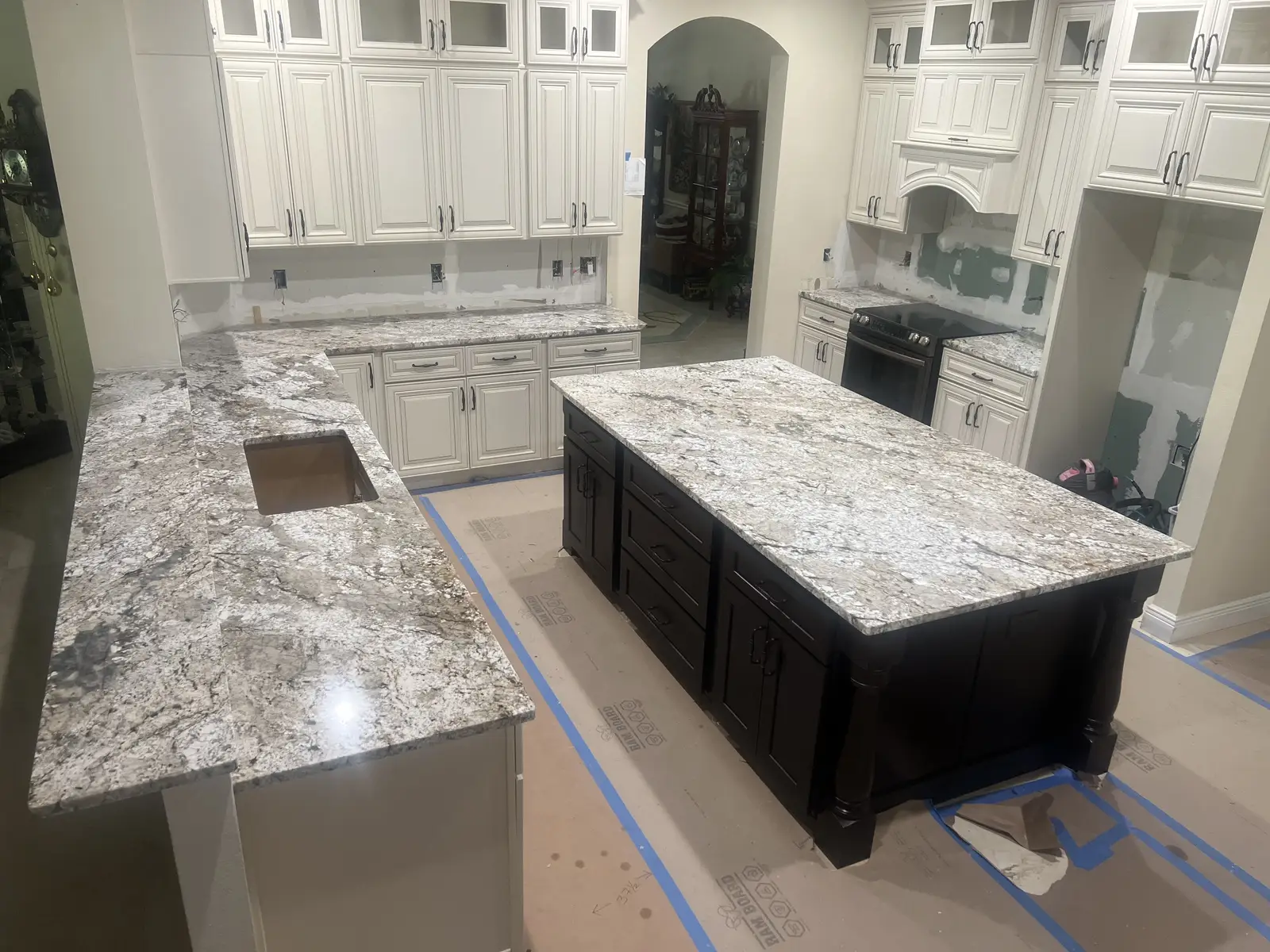 Granite island countertop with dark wood cabinetry installed by Venet LLC in Tampa Bay, Florida
