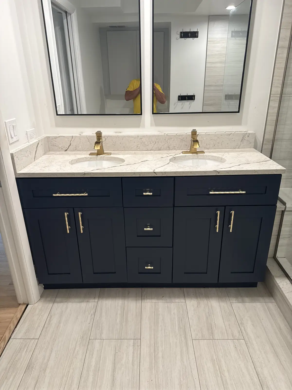 Navy double vanity with marble-look countertop and gold faucets by Venet LLC in Tampa Bay, Florida