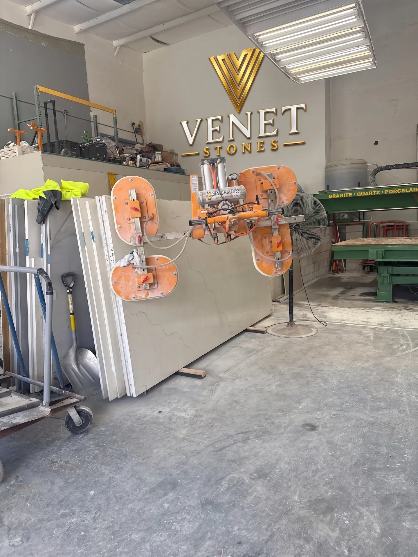 Countertops — Venet Stones workshop with vacuum lifter and marble slabs beneath the company logo